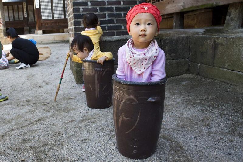 Jung Ha-yoon, 2, is pictured in a ceramic container while playing with other children at the traditional sports square during the Royal and Aristocrat's Traditional Food Festival held at Unhyeon Palace in Seoul. Jacquelyn Martin / Reuters