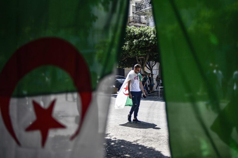 A man draped in an Algerian national flag walks along a street as protesters take part in a demonstration in Algiers. AFP