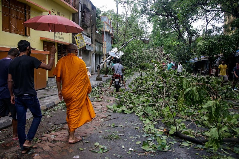 A Buddhist monk walks through a road laid with fallen trees and branches after Cyclone Amphan hit the region in Kolkata, India. A powerful cyclone ripped through densely populated coastal India and Bangladesh, blowing off roofs and whipping up waves that swallowed embankments and bridges and left entire villages without access to fresh water, electricity and communications. AP Photo