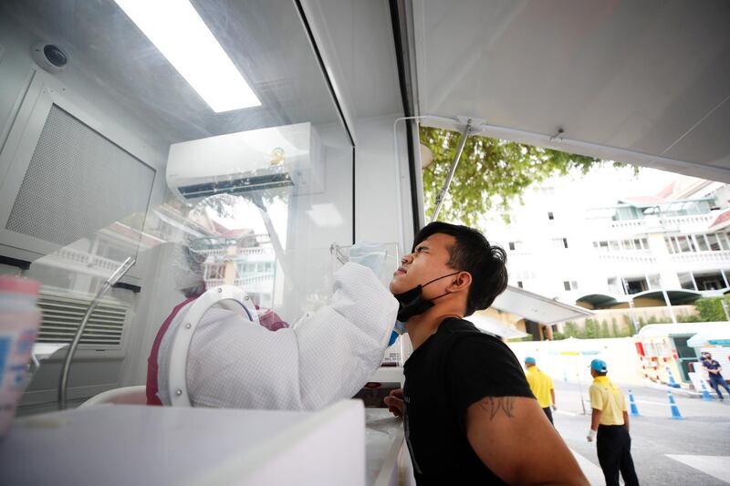 Thai health officials take samples from workers during a Covid-19 test drive outside a shopping mall in Bangkok. EPA