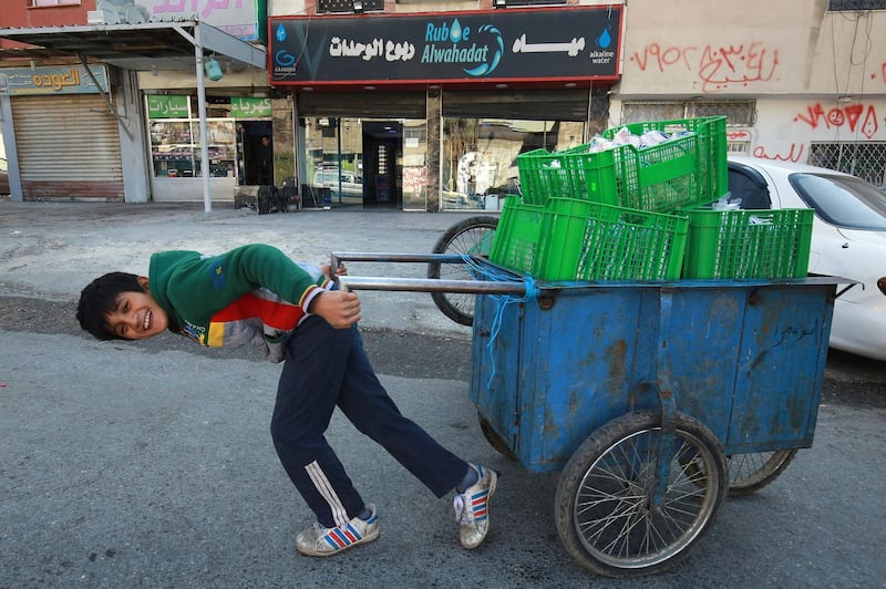 A Jordanian youth uses a hand cart to work in Amman's Wahdat district. Many minors have been forced prematurely into the labour market in Jordan due to the Covid-19 pandemic, experts say. Schools in Amman and throughout the country have been closed for nearly a year now, while economic fallout from the pandemic has eaten into breadwinners' ability to feed their families. AFP