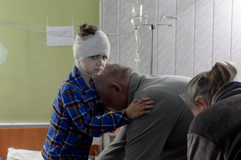 Misha, 5, who lost his mother some weeks ago and got injured during a Russian strike, is helped by his grandfather to dress up in the basement of a hospital in Mykolaiv. AFP