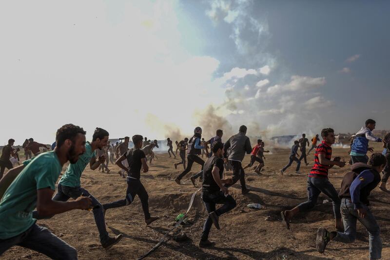 epa06741649 Palestinian protesters run for cover from Israeli tear-gas during clashes after near the border with Israel in the east of Gaza Strip, 15 May 2018 (issued 16 May 2018). According to Palestinian medical sources, two Palestinian protesters were shot dead by the Israeli army on 15 May in Gaza, while thousands of Palestinians attended the funerals for some 25 of the 60 protesters killed a day earlier by the Israeli army during mass demonstrations. Palestinians are marking the Nakba Day, or the day of the disaster, when more than 700 thousand Palestinians were forcefully expelled from their villages during the war that led to the creation of the state of Israel on 15 May 1948. Protesters call for the right of Palestinians to return to their homeland.  EPA/MOHAMMED SABER