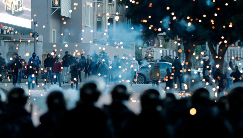 Supporters of Lebanon's Shiite Hezbollah and Amal groups (background) throw fireworks towards Lebanese riot police during clashes on December 14, 2019, in central Beirut. AFP