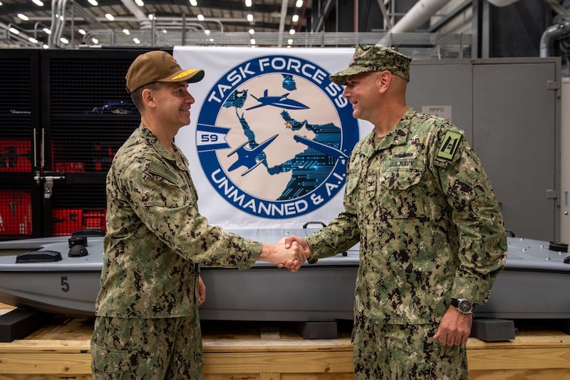 Vice Adm Brad Cooper, left, commander of US Naval Forces Central Command, shakes hands with Capt Michael Brasseur, the first commodore of Task Force 59, the first unit to integrate unmanned systems in the region.
