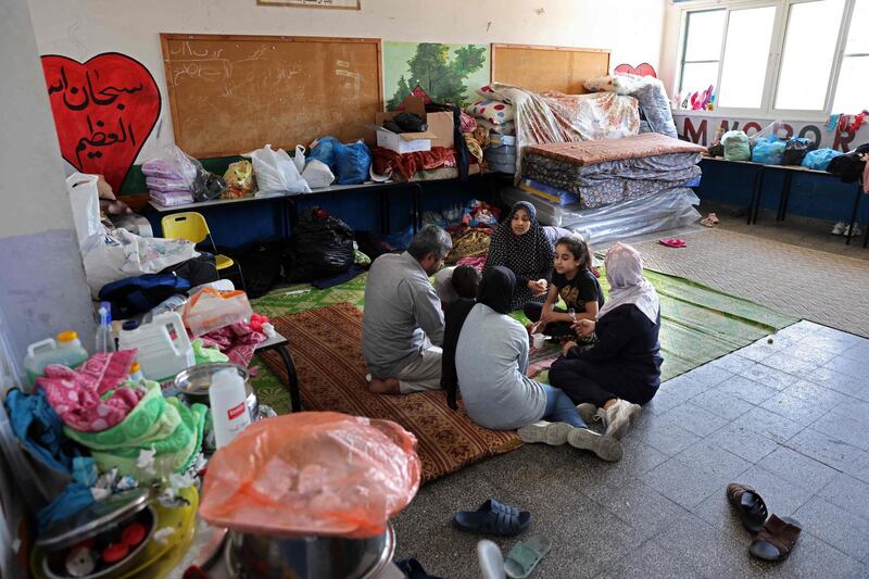 Palestinian Mansour Abu Ghadyan and his family share a meal in the classroom that they call home after theirs was destroyed by an Israeli air strike. AFP