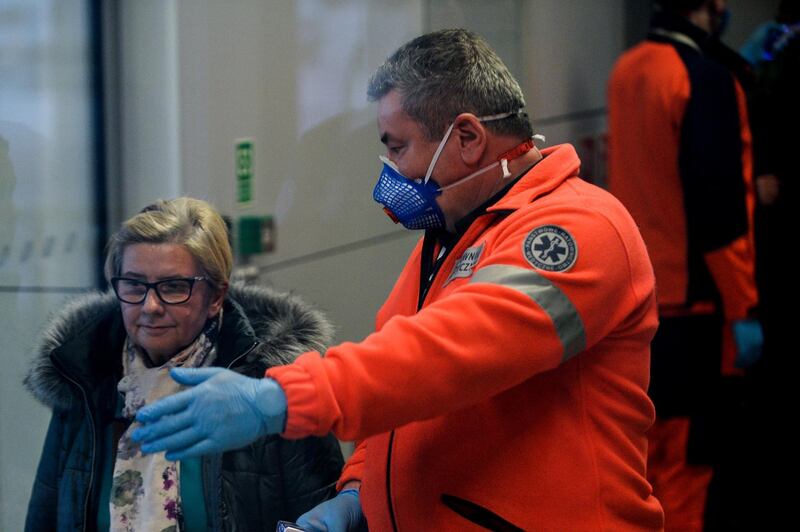 A passenger who had high temperature stands on the side before a second temperature test as she arrived from Milan Bergamo to Krakow International Airport.  Getty