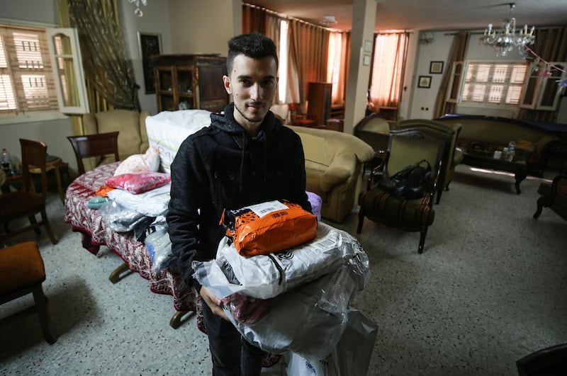 Twenty one year-old Majdi Al Rayass checks goods that he received from a shipping company, before delivering them to customers. Majd Mahmoud/The National