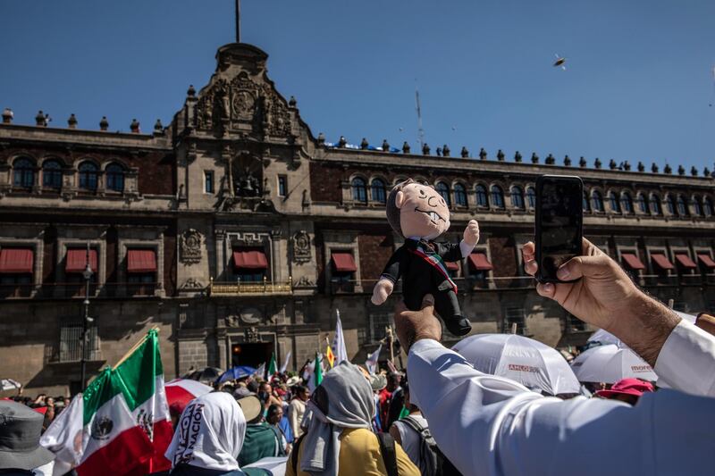 A supporter takes a photograph of a stuffed doll in the likeness of Andres Manuel Lopez Obrador at the central plaza, known as the Zocalo, in Mexico City. Bloomberg