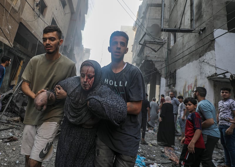 An injured woman is helped leave Al Shati refugee camp after an Israeli rocket attack. EPA