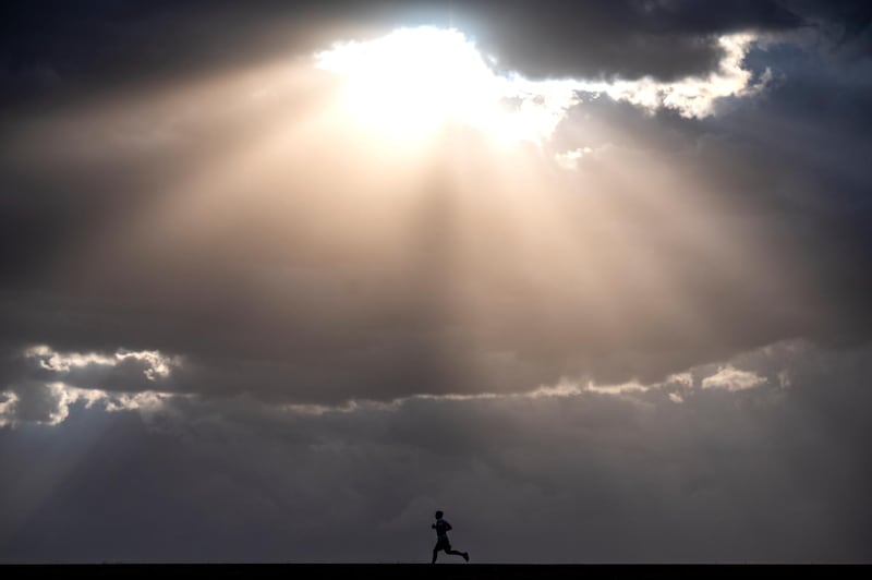 Sunshine breaks through the cloud cover as a runner jogs along the Lewiston Levee Parkway Trail in Lewiston, Idaho.  AP