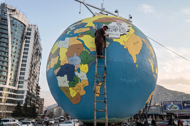 A painter gives the final touches to a large globe installed by municipal authorities at Dahan-e Bagh square in Kabul. AFP
