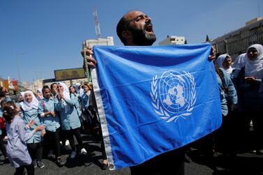 A Palestinian demonstrator holds a United Nations flag during a protest against US funding cuts. Reuters