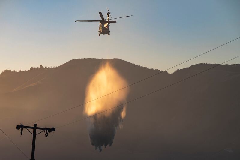 A helicopter drops water on the fire near Aromas, California.  AP