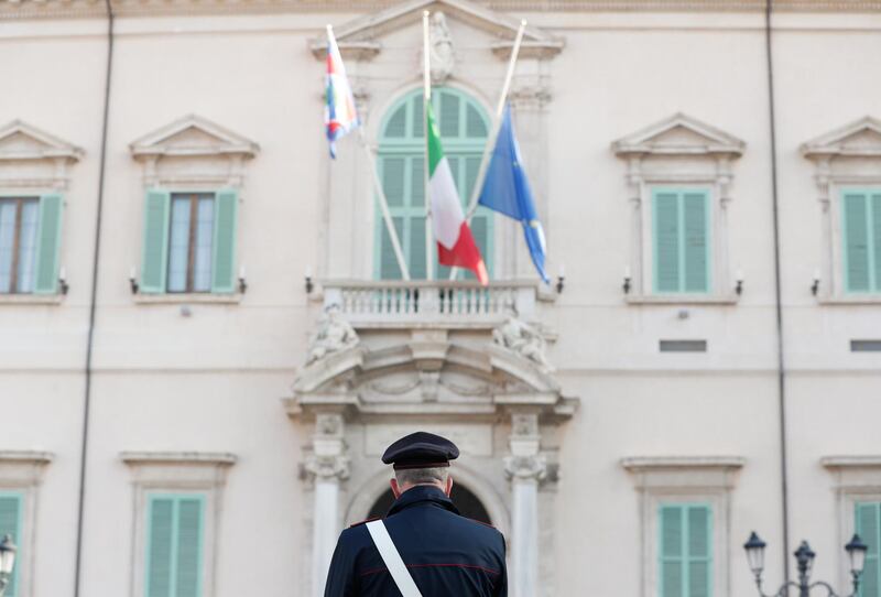 A Carabinieri officer looks at the Italian flag that flies at half mast next to EU and Presidential Standard of Italy flags, outside the Presidential Quirinale Palace, following the death of the Italian ambassador to the Democratic Republic of Congo Luca Attanasio, Italian military policeman Vittorio Iacovacci and their Congolese driver, who were killed in an attack on a United Nations convoy in eastern Congo, in Rome, Italy, February 23, 2021. REUTERS/Yara Nardi