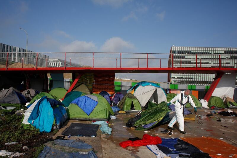 A Paris town hall worker clears a migrant makeshift camp, in Paris, France. Thibault Camus / Reuters