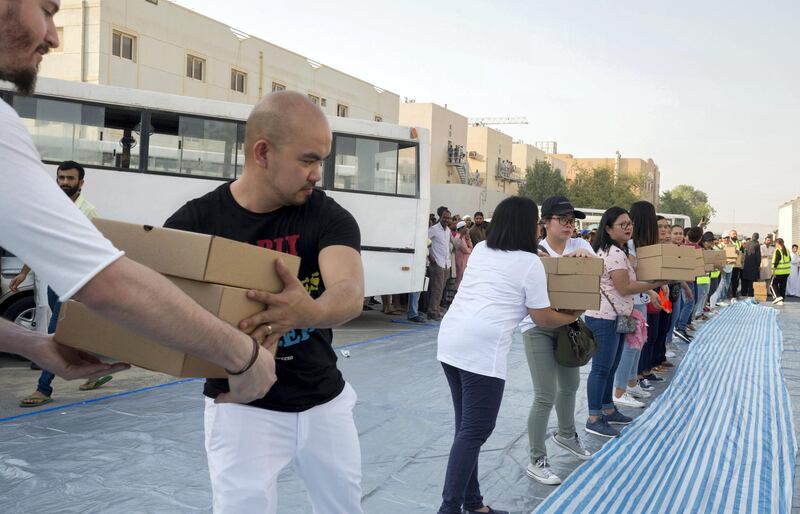 DUBAI, UNITED ARAB EMIRATES -  Volunteers with iftar meal boxes arrange them where the workers will be seated to break their fast.  Dubai Police join hands with Berkeley Assets to serve up Iftar dinner to mark Laylatul Qadr for 10,000 labourers with seating for 5,000 and another 5,000 laborers will go home with meal boxes in Al Muhaisnah, Dubai.  Ruel Pableo for The National