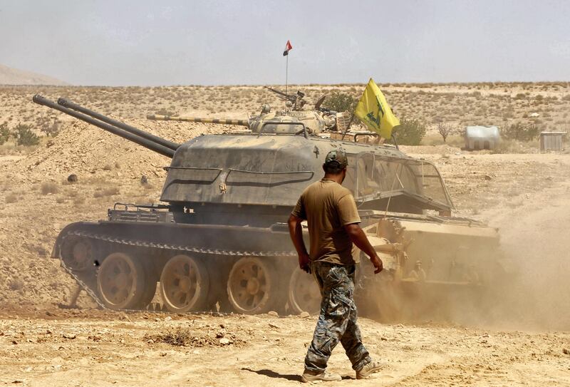 A fighter walks past a tank bearing a Hezbollah flag in the Qara area, in Syria's Qalamoun region, on August 28, 2017. / AFP PHOTO / LOUAI BESHARA