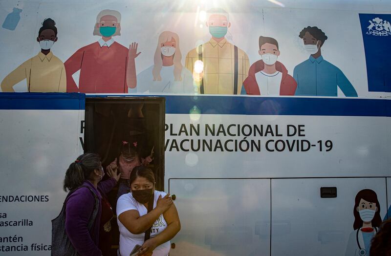 Women leave a bus being used as a Covid-19 vaccination clinic in Santiago, Chile. AP Photo