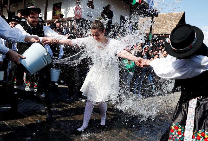 A woman in traditional dress has water thrown on her during a traditional Easter celebration in Holloko, Hungary. Reuters