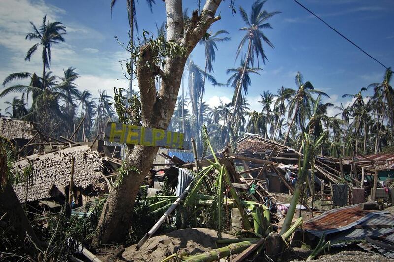 Destroyed houses and trees with a slogan calling for help are seen along a road in the village of Mantang, Taft town Eastern samar province central Philippines, a day after typhoon Hagupit hit the province. Vincent Go / AFP