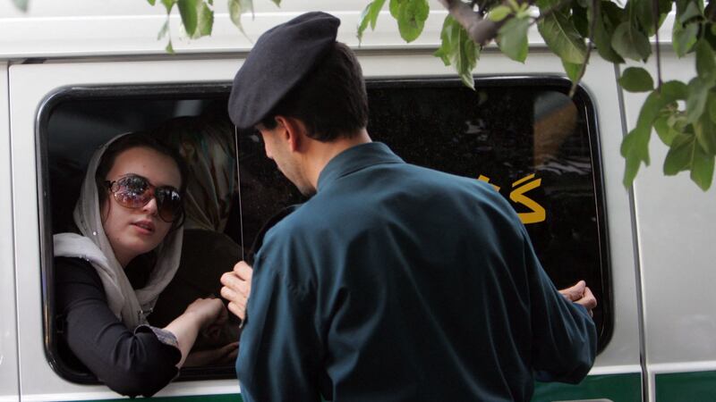 An Iranian police officer speaks with a woman after she was detained over "inappropriate" clothes during a crackdown to enforce the dress code in Tehran. AFP