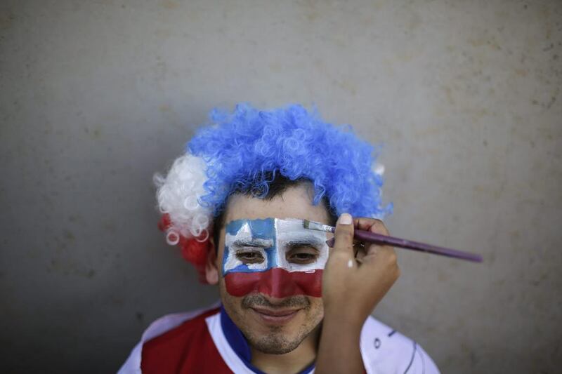 A football fan sits still, as his face is painted to represent the Chilean national flag. Felipe Dana / Reuters