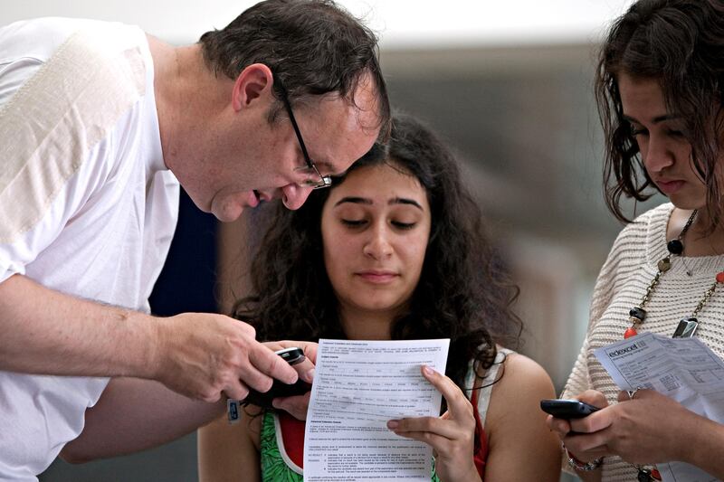 Dubai, August 18, 2011 - Hannah Felton (C) looks over her A Level's test scores while her father, Jonathan helps her understand the scores as Felton's friend, Reema Musa looks over her tests scores at the Dubai British School  in Dubai, August 18, 2011. (Jeff Topping/The National) 