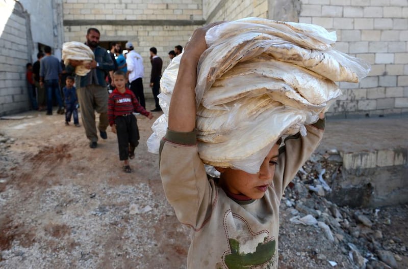 A boy carries bread in the northern Syrian town of Atareb, Aleppo province, in November 2012. One of Syria's militant groups, Jabhat Al Nusra, tries to employ soft power, and it implemented a bread distribution programme in Aleppo city that same year. Philippe Desmazes / AFP