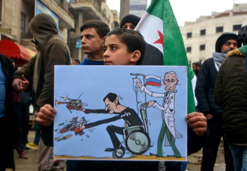 A young Syrian holds a caricature representing Syrian President Bashar al-Assad and Russian President Vladimir Putin as he takes part in a demonstration to protest against the continuing assault by the Syrian regime and Russian forces on the last rebel-held pockets in the northern Idlib province, in the city of Idlib.   AFP