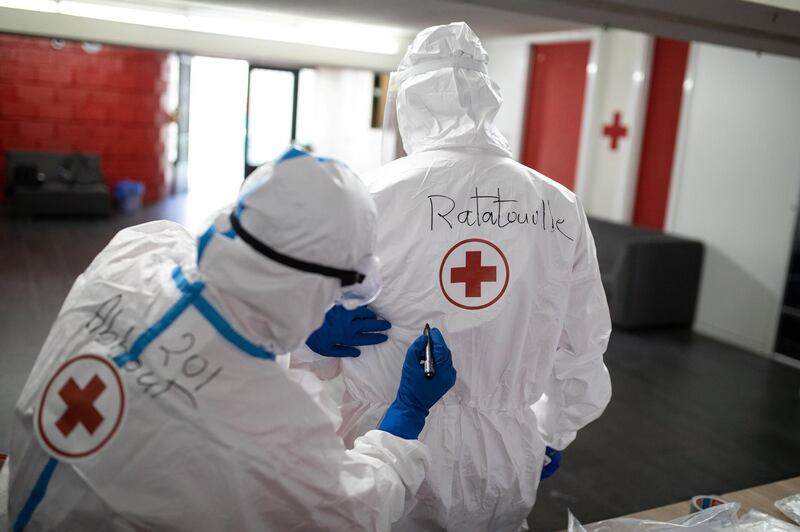 ©2021 Tom Nicholson. 23/01/2021. Jounieh, Lebanon. Lebanese Red Cross volunteer paramedic David ÒAbboutÓ Ayache (left) writes his colleague PatrickÕs nickname ÒRatatouilleÓ on his Coronavirus PPE at the Jounieh station. DavidÕs nickname means ÒgrasshopperÓ, and his day job is working as an internet provider, whilst Patrick ÒRatatouilleÓ Khoueiry got his nickname as he works a chef in a hotel in the Achrafieh district of Beirut when he isnÕt volunteering. Today Lebanon registered 4176 new Coronavirus cases, and 52 deaths. Tom Nicholson for The National