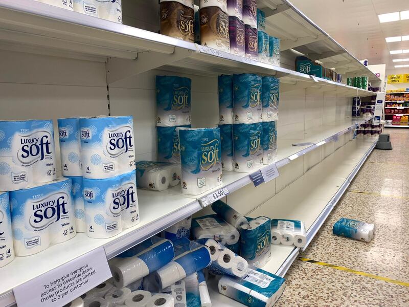 A sign limiting shoppers to one item per customer is displayed on near-empty shelves for toilet paper rolls in a supermarket in Birkenhead, Merseyside. AFP