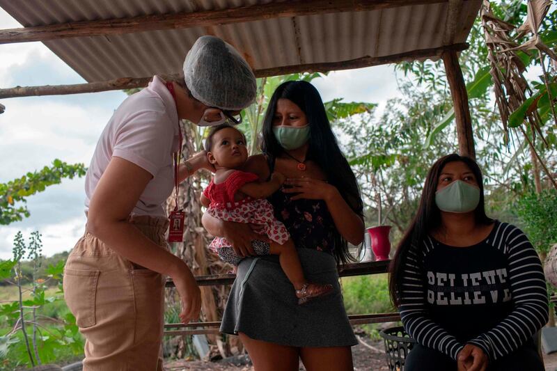 Physician Carolina Xavier, left, a member of the indigenous medical care unit of the Sao Mata Verde Bonita tribe, speaks with patients in Marica, Rio de Janeiro state. AFP