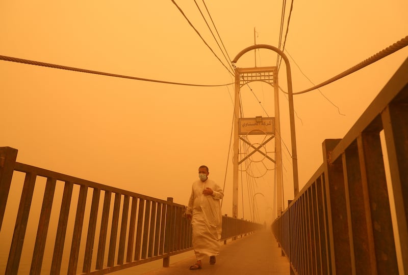 A man walks along a pedestrian bridge across the Euphrates river during a heavy dust storm in Nasiriyah. AFP