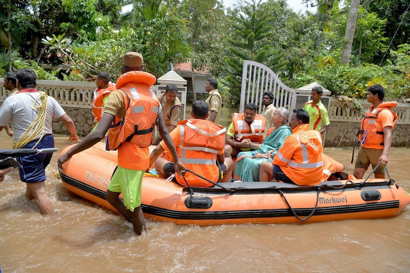 Kerala and Tamil Nadu Fire Force personnel ferry children and eldery in a dinghy through flood waters during a rescue operation in Annamanada village in Thrissur District, Kerala. AFP