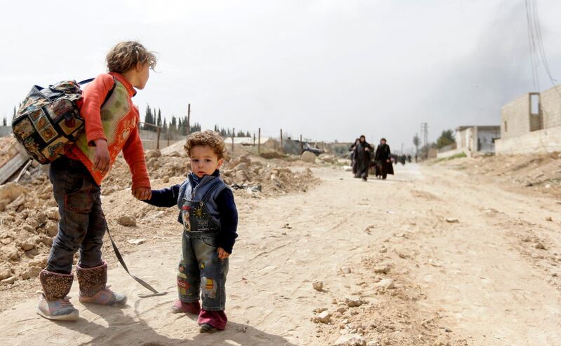 Syrian children wait for other civilians to catch up as they pass through a regime-controlled corridor opened by government forces in Hawsh Al Ashaari, east of Hamouria, on March 15, 2018. Louia Beshara / AFP