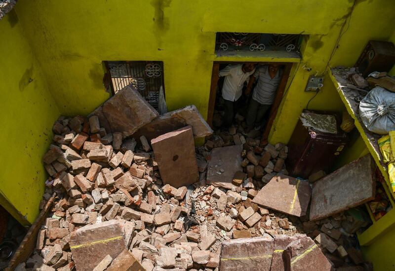 Neighbours look up at the roof which collapsed in the home of Sunil Kumar in Agra. Chandan Khanna / AFP