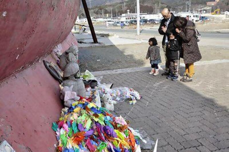A family prays for the victims of the March 11, 2011 earthquake and tsunami in front of the 330-tonne fishing vessel Kyotoku Maru No 18 which was flung 800 metres inland from Kesennuma port by the tsunami in Kesennuma, Miyagi Prefecture on Saturday. Shizuo Kambayashi / AP Photo