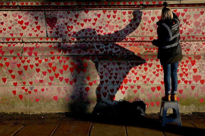 A volunteer paints hearts on the Covid Memorial Wall in London. AP Photo