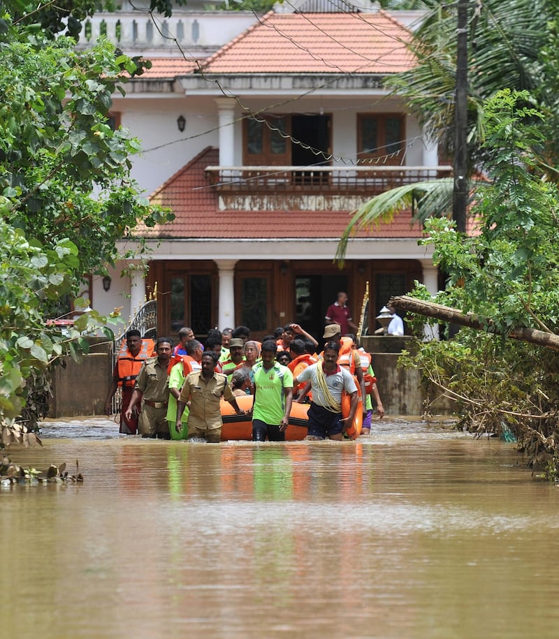 Kerala and Tamil Nadu Fire Force personnel transport children and elderly people in a dinghy through flood waters during a rescue operation in Annamanada village in Thrissur District, Kerala. AFP