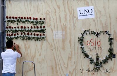A man arranges flowers next to a graffiti marking a bomb attack in the centre of Oslo on July 28, 2011, where Anders Behring Breivik killed 76 people. Reuters