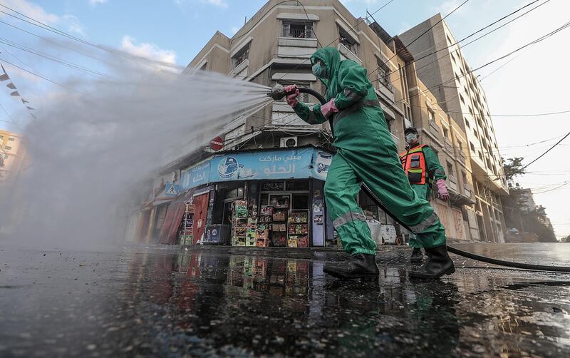A Palestinian sprays disinfectant against the spread of Covid-19 in the streets in Gaza City, Gaza Strip.  EPA