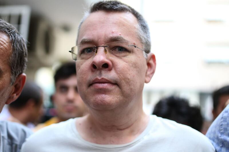 (FILES) In this file photograph taken on July 25, 2018, US pastor Andrew Craig Brunson is escorted by Turkish plain clothes police officers to his house in Izmir. - Only weeks ago it would have seemed fanciful to draw a link between the fate of an American evangelical pastor in Turkey, a crisis in bilateral ties of two NATO allies and turmoil on global financial markets. But Andrew Brunson, a Protestant clergyman who had lived in Turkey for a quarter of a century without disturbance, has now found himself at the centre of a bitter dispute between Washington and Ankara that caused the lira to crash and the economic jitters to spread globally. Brunson's world was turned upside down on October 7, 2016 when he and his wife Norine were arrested in the crackdown that followed the failed July 15 coup bid that year aimed at toppling President Recep Tayyip Erdogan. (Photo by - / AFP)