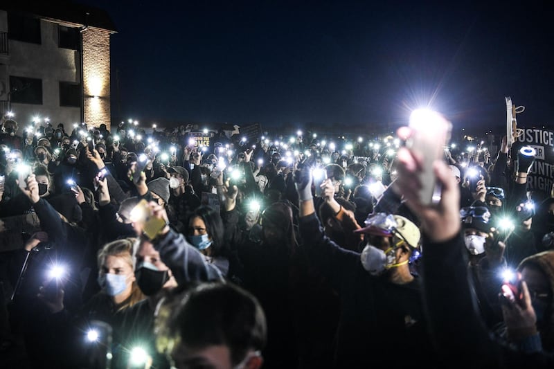Demonstrators hold up their phones with the light shining near the Brooklyn Center police station during the sixth night of protests over the shooting death of Daunte Wright by a police officer in a Minneapolis suburb.  AFP