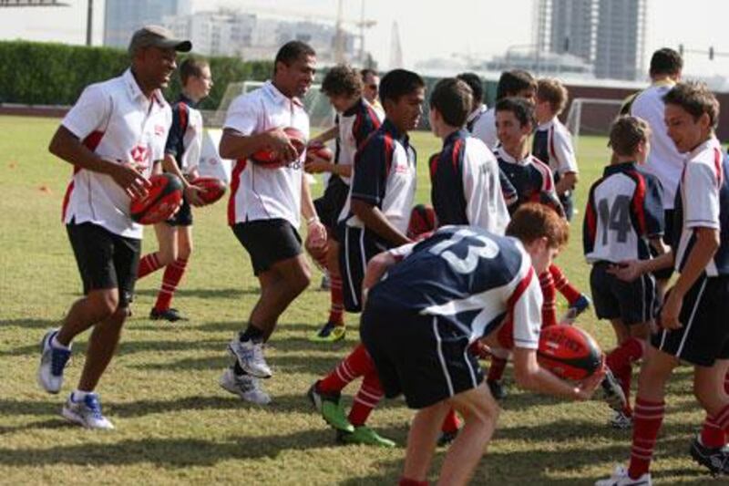 Former rugby players Jason Robinson, third from left, and George Gregan, far left, have some fun with pupils of Dubai College during their training session in Dubai on Tuesday.