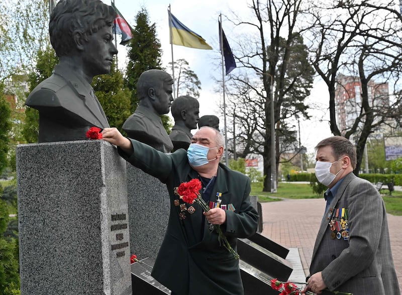 Former liquidators of the Chernobyl nuclear accident wearing face masks lay flowers at Chernobyl's memorial in Kiev amid the Covid-19 coronavirus pandemic. AFP