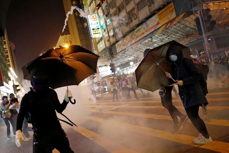 Anti-government protesters hold umbrellas as they protest amid tear gas on Christmas Eve at Tsim Sha Tsui in Hong Kong, China, December 24, 2019. REUTERS/Tyrone Siu