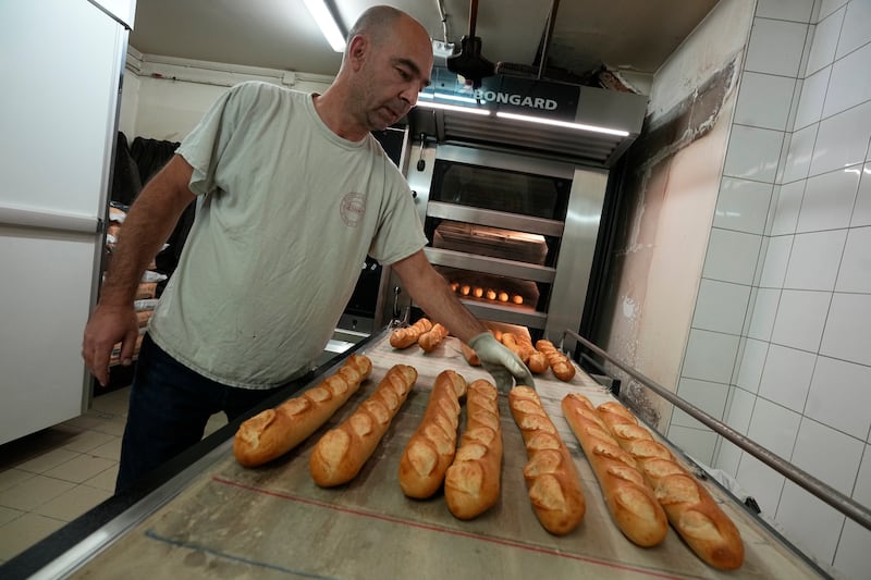 A baker takes baguettes out of an oven at a bakery in Versailles. The French baguette has been given Unesco World Heritage status. AP