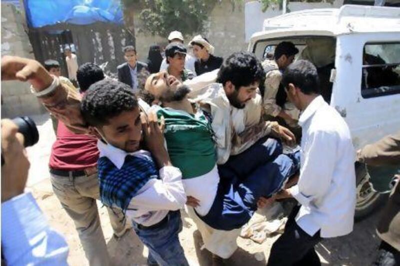 Medics carry a wounded anti-government protester after clashes with security forces in Sanaa yesterday. Khaled Abdullah / Reuters