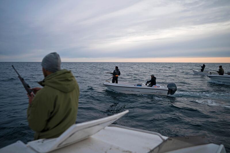 Mugu Utuaq, left, reloads his rifle as he rides with other boats hunting whales near Kulusuk.